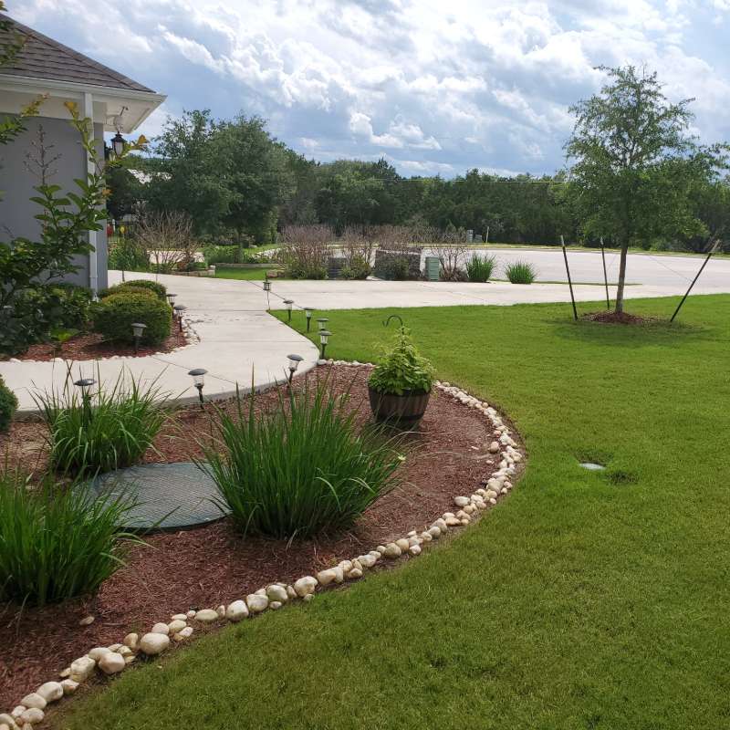 Front-yard landscape design with ornamental grasses and river-rock border, Austin TX