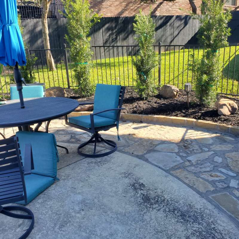 Flagstone patio with outdoor furniture and umbrella in a Travis County backyard